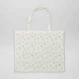 Bolso tipo tote bag de tela color crudo con estampado de flores pequeñas en tonos rosa y amarillo.