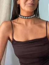 Choker negro trenzado con tiras símil gamuza, decorado con pedrería facetada ovalada con engarce dorado.