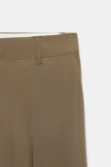 Pantalón de tiro bajo color marrón, con bolsillos frontales, falsos bolsillos traseros de vivo y cierre delantero con cremallera y gancho metálico.