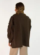 Sweater de punto color bordó, con cuello redondo, mangas largas abullonadas y detalle de flecos en las costuras de los hombros.