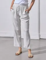 Pantalón de lino color beige con rayas verticales blancas, pretina elastizada con cordón ajustable, bolsillos laterales y ruedo con botamanga.