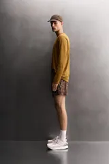 Shorts deportivos de Zara Athleticz confeccionados en tejido técnico ligero con estampado camuflado en tonos marrones y naranjas. Poseen cintura elástica ajustable, forro interior y aberturas en el bajo.