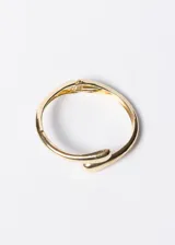 Pulsera brazalete rígido dorado con terminaciones redondeadas y cierre con bisagra.