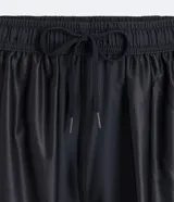 Bermuda deportiva gris con cintura elástica, cordón de ajuste, bolsillos con cremallera, recorte lateral con agujeritos y abertura en el bajo.