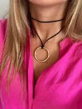 Gargantilla negra con dije de aro dorado.