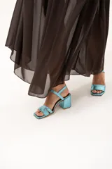 Sandalia de tacón cuadrado medio, color turquesa metalizado, con diseño de tiras anchas en el empeine y cierre con pulsera al tobillo.