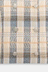 Blazer de cuello redondo y manga larga, con diseño a cuadros en tonos beige, azul y negro. Presenta cierre frontal cruzado con botones metálicos y corte recto.