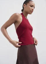 Top de punto fino con cuello halter y espalda descubierta con detalle de aro metálico. Diseño entallado sin mangas.