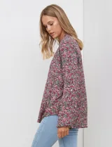 Blusa de manga larga con estampado floral pequeño en tonos rosados, morados y azules, escote en V y detalle de botones frontales.