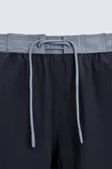 Bañador de hombre azul marino con cintura elástica gris y cordón ajustable. Presenta un pequeño texto estampado en relieve en la parte inferior izquierda.