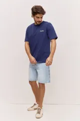 Remera blanca de algodón, de corte holgado y mangas cortas, con pequeño estampado azul en el pecho.