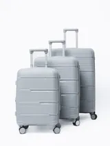 Valija rígida de viaje color gris con diseño de líneas horizontales. Cuenta con manija extensible, ruedas giratorias y cierre con combinación.