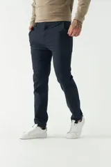 Pantalón chino color beige, de corte slim, con bolsillos laterales y traseros. Se ajusta a la cintura con cinturón de cuero marrón.