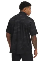 Polo de golf Under Armour modelo Playoff 3.0, con diseño de camuflaje en tonos negros y grises. Presenta cuello clásico, tapeta de tres botones y logo de la marca en el pecho. Confeccionado en tejido técnico transpirable y elástico con protección solar.