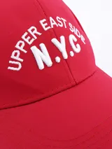 Gorra roja con visera, con bordado frontal de la inscripción "Upper East Side N.Y.C." en color blanco.