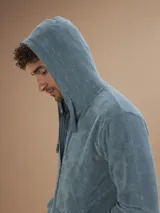 Campera con capucha de toalla color celeste, con cierre frontal completo y bolsillos laterales.