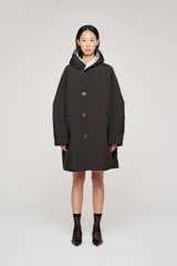 Campera reversible de corte regular, confeccionada en nylon con acabado repelente al agua. Presenta diseño con capucha, mangas raglán y cierre frontal con botones. Un lado es de color negro con bolsillos de parche, mientras que el reverso es de color plateado con bolsillos laterales integrados.