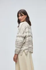 Buzo de tejido de punto con diseño de rayas horizontales en tonos beige y blanco, cuello redondo, hombros caídos y mangas largas.