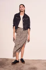 Campera de denim gris oscuro con tachas plateadas en cuello y solapas, corte cropped y mangas largas.