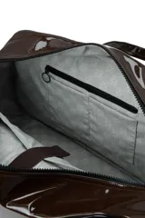 Bolso de fin de semana tipo duffle, confeccionado en material sintético efecto charol color marrón oscuro. Cuenta con doble asa superior, correa ajustable extraíble, cierre principal y logo de la marca estampado en el frente.