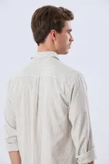 Camisa de lino rayada de manga larga, con cuello camisero, cierre frontal de botones y bordado sutil en el pecho.