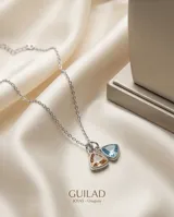 Collar de cadena fina de acero con dos dijes colgantes en forma de triángulo, uno con circonia color naranja y otro con circonia color celeste.