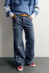 Jeans flare fit de denim azul oscuro con roturas y costuras decorativas en las perneras. Tiro medio y diseño de cinco bolsillos.