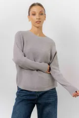 Buzo tejido de punto en color beige, con cuello redondo, mangas largas y silueta relajada con dobladillo irregular, siendo más largo en la parte trasera.