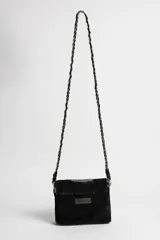 Cartera bandolera de cuero negro con solapa, decorada con apliques bordados de lentejuelas y abalorios plateados en el centro. Incluye una correa larga de hombro estilo cadena trenzada.