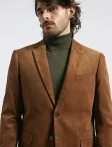 Saco sport de pana color marrón, con cuello de solapa, cierre frontal de dos botones, bolsillos laterales con tapa y puños con botones.