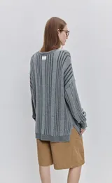 Sweater de punto color gris con diseño de rayas verticales oscuras, cuello redondo y calce relajado de mangas largas.