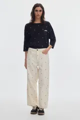 Jean de mezclilla color crudo con estampado de lunares negros, corte barrel de pierna ancha que se estrecha hacia el tobillo, tiro medio y costuras en hilo color oro.