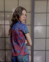 Top de tafeta elastizada con estampado floral, cuello mao con ribete en contraste, mangas cortas y cierre frontal cruzado con botones a la vista.