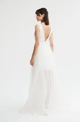 Vestido corto de color blanco con escote en V pronunciado, detalles de encaje en el torso y tirantes anchos con apliques. Presenta una falda corta de encaje con diseño recto.