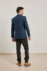 Blazer azul de corte slim, confeccionado en tejido con mezcla de lana. Tiene cuello con solapas, manga larga con puños abotonados, bolsillos de solapa en la cadera, abertura en la espalda y cierre frontal con botones.