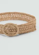 Cinturón de fibras naturales trenzadas en color beige, con hebilla redonda forrada en el mismo material y detalle de eslabones metálicos en el centro.