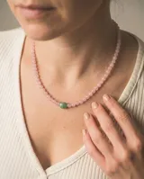 Collar de cuentas de cuarzo rosa con una piedra central verde y cierre de plata.