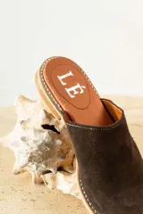 Mules de cuero negro con tachas plateadas en el borde de la suela y plantilla con logo estampado.
