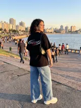 Remera negra de algodón con corte oversize y estampado frontal con la palabra "Blessed" en blanco y "by God" en rojo.