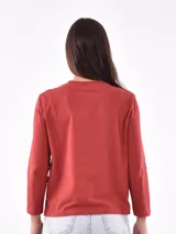 Remera de manga larga color blanco, con cuello redondo y estampa frontal en tono rosado que incluye un diseño de marco con moño y la frase "live simply love sincerely".