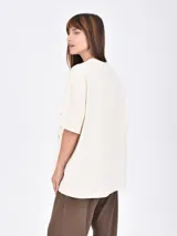 Remera de manga corta color crema, con cuello en V y estampado frontal de estilo universitario con texto "UNIVERSITY Boston 68 MASSACHUSETTS".