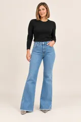 Jeans de denim azul con diseño flare, tiro alto, bolsillos delanteros y traseros, y terminaciones desflecarse en el bajo.