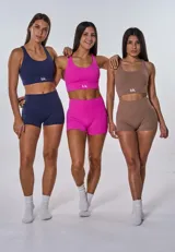 Conjunto deportivo compuesto por un top de escote redondo con espalda estilo nadador y un short de tiro alto. Ambas piezas son de color beige oscuro y cuentan con el logo de la marca estampado en blanco.