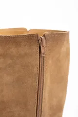 Bota de caña alta color camel, confeccionada en gamuza. Presenta una suela de goma gruesa y plana, y un diseño liso sin cierres visibles.