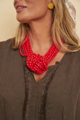 Collar corto de múltiples tiras de cuentas rojas entrelazadas formando un nudo central.