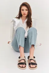 Sandalias de estilo deportivo con plataforma plana negra. Presentan un diseño de tiras anchas con cierre de velcro, combinando cuero texturizado blanco con detalles en cuero metalizado plateado.