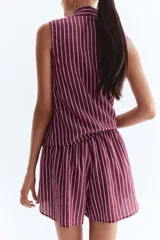 Short holgado de tela liviana color morado con finas rayas verticales blancas. Presenta cintura elástica fruncida con cordón ajustable y bajo redondeado con aberturas laterales.