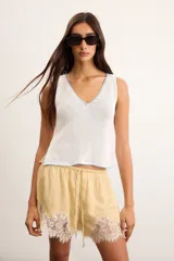 Musculosa de punto color blanco con escote en V y detalles de bordado artesanal en celeste en el cuello y el ruedo.