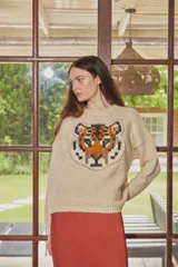 Sweater de lana color crudo con diseño de cabeza de tigre bordado en el frente. Presenta cuello redondo, mangas largas con hombros caídos y puños acanalados.