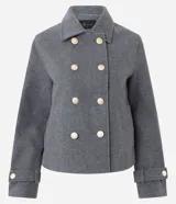 Saco corto de corte regular confeccionado en polivelour gris, con cuello inglés, cierre frontal de doble abotonadura con botones dorados y mangas largas con detalle de trabas en los puños.